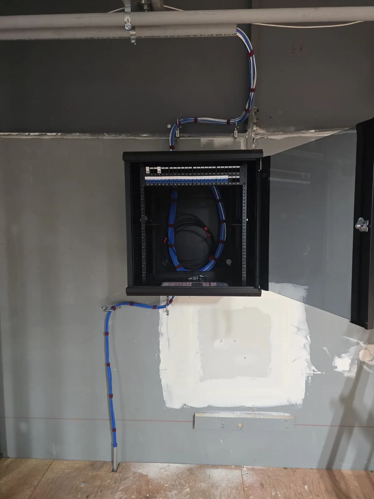 Network cabinet rough-in with neatly routed blue and white cabling