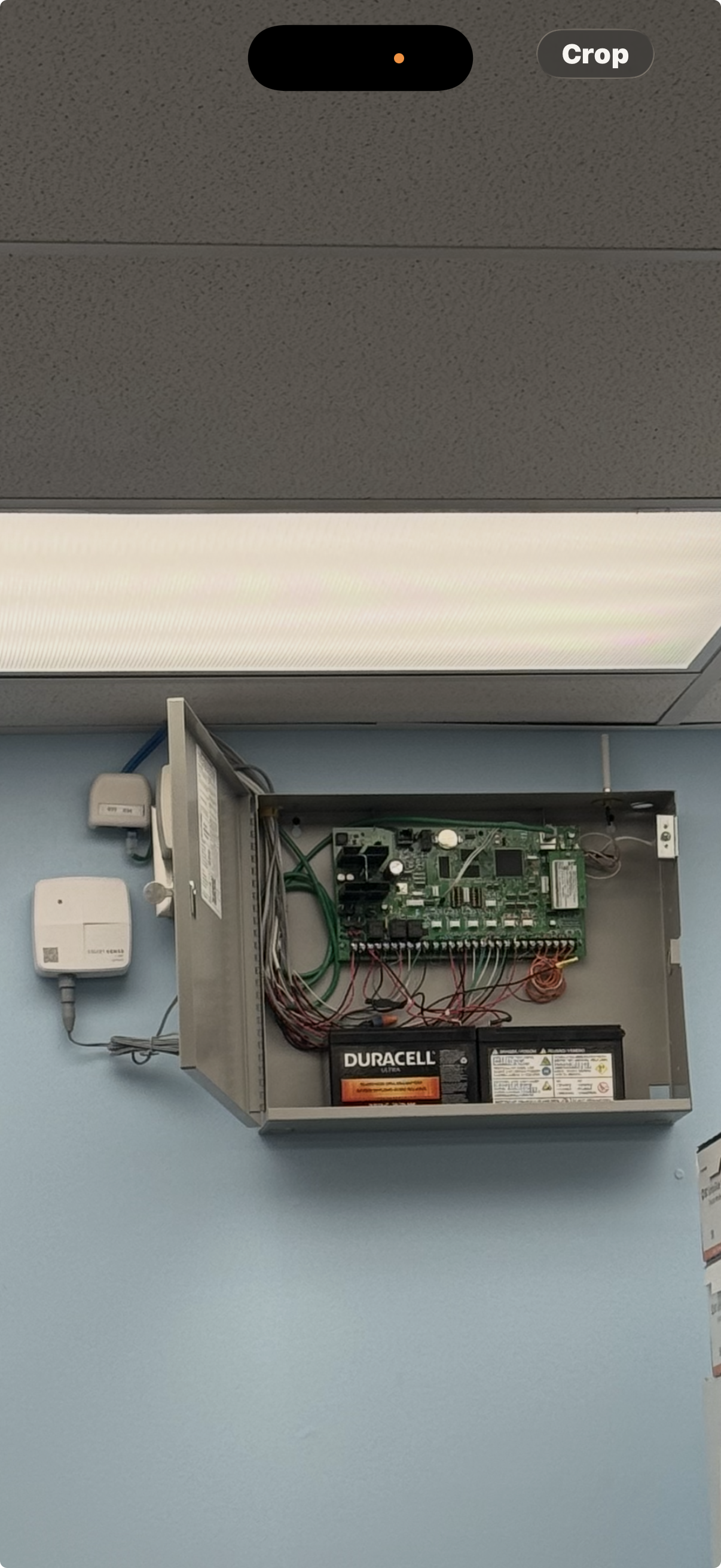 Open commercial intrusion-alarm control panel with field wiring and backup batteries